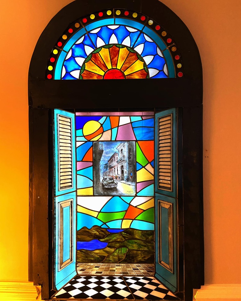 Stained glass window with arched transom, Havana street scene, and geometric patterns